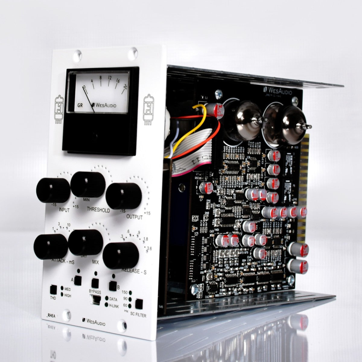 A white and black WesAudio RHEA audio module with multiple black rotary knobs, a front analog meter, and a visible internal black circuit board with red, yellow, and silver components, photographed on a clean white background.