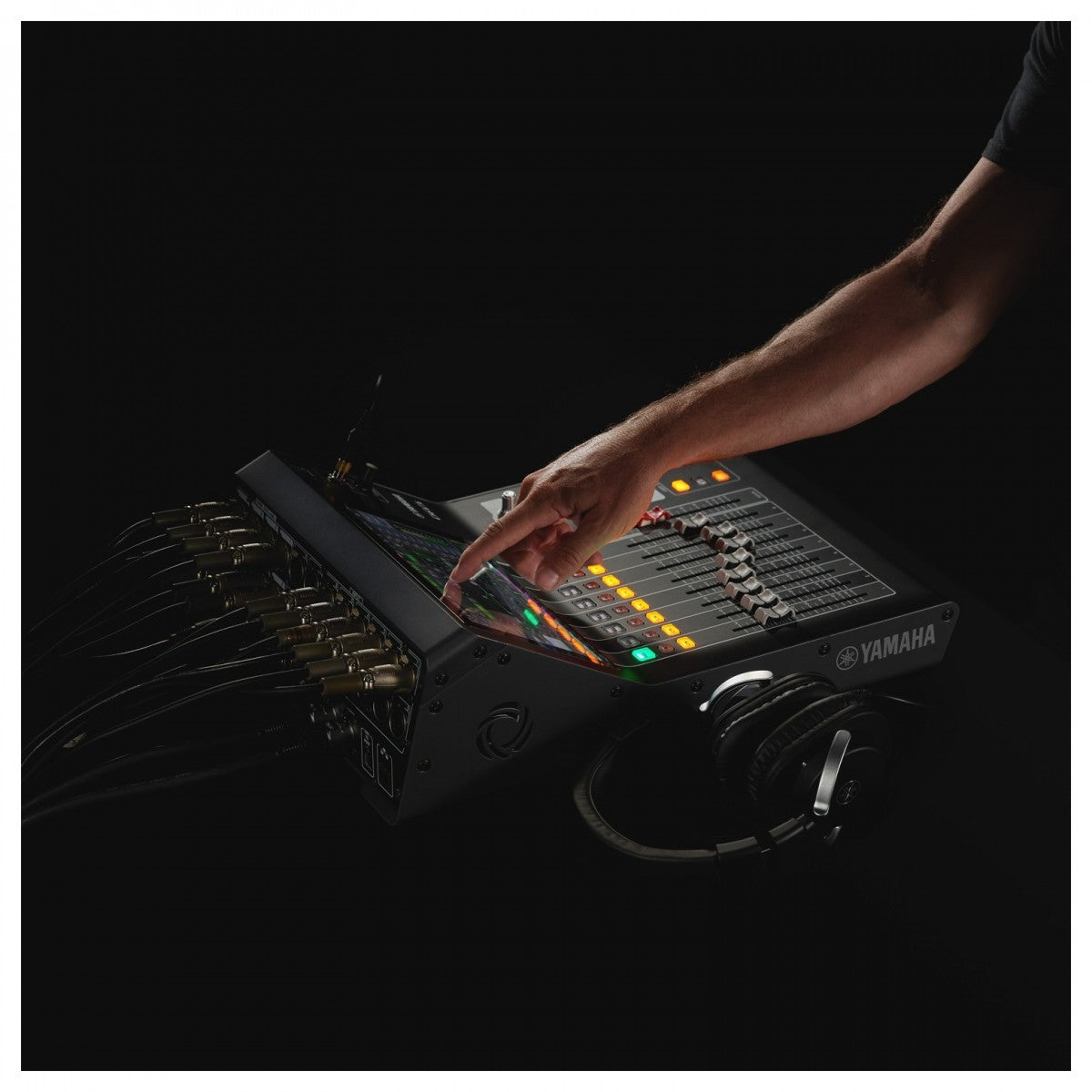 Hand adjusting knobs on a Yamaha audio mixing console with a dark background