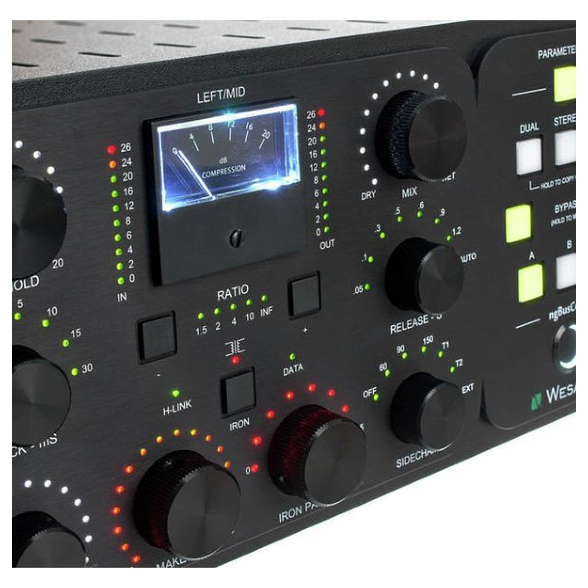 Close-up of a black audio or signal processor control panel with multiple rotary knobs, illuminated green and red indicator lights, a central analog-style compression meter, and white text labels on a white background.